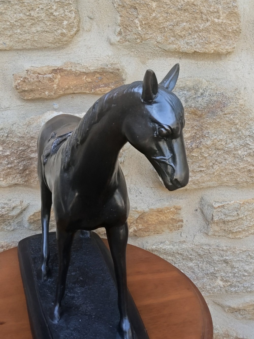 A dark brown cast bronze sculpture depicting a saddled standing horse positioned on an integral rectangular base. View V