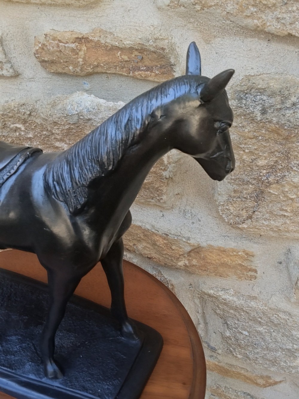 A dark brown cast bronze sculpture depicting a saddled standing horse positioned on an integral rectangular base. View VI