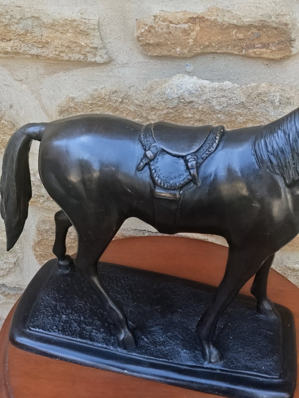 A dark brown cast bronze sculpture depicting a saddled standing horse positioned on an integral rectangular base. View IX