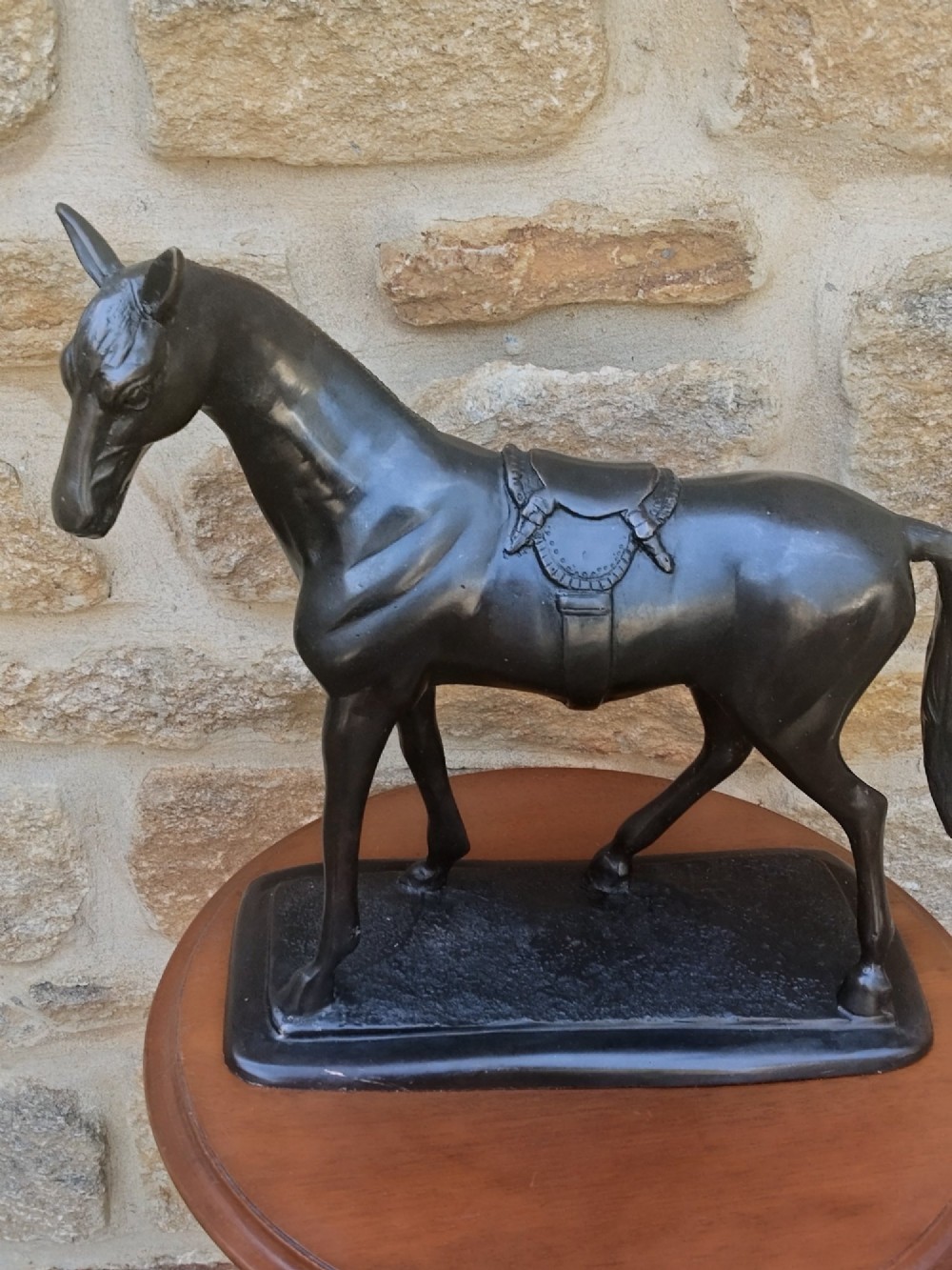 A dark brown cast bronze sculpture depicting a saddled standing horse positioned on an integral rectangular base. View XI