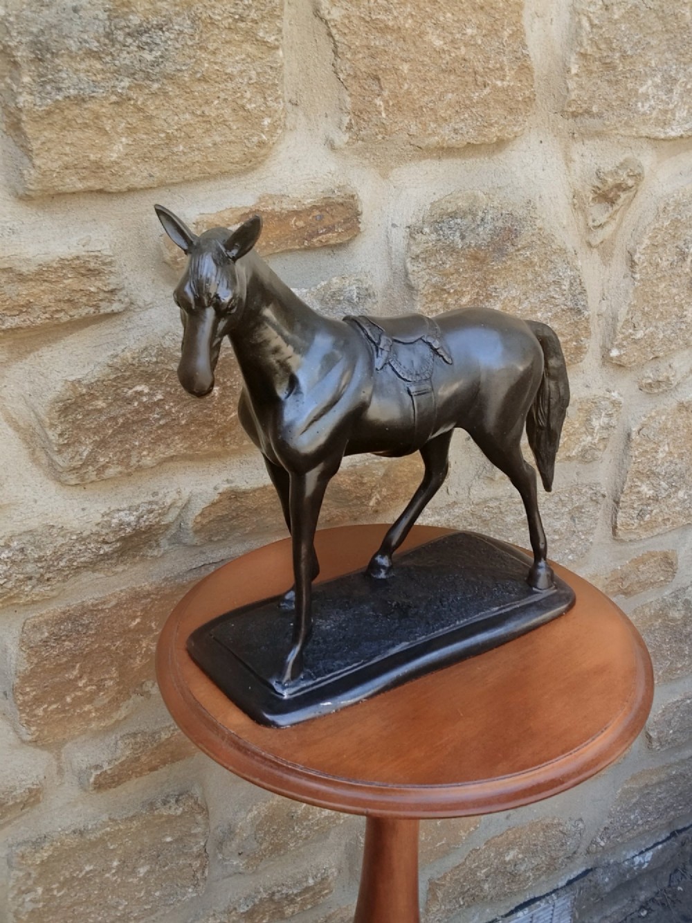 A dark brown cast bronze sculpture depicting a saddled standing horse positioned on an integral rectangular base. View XII