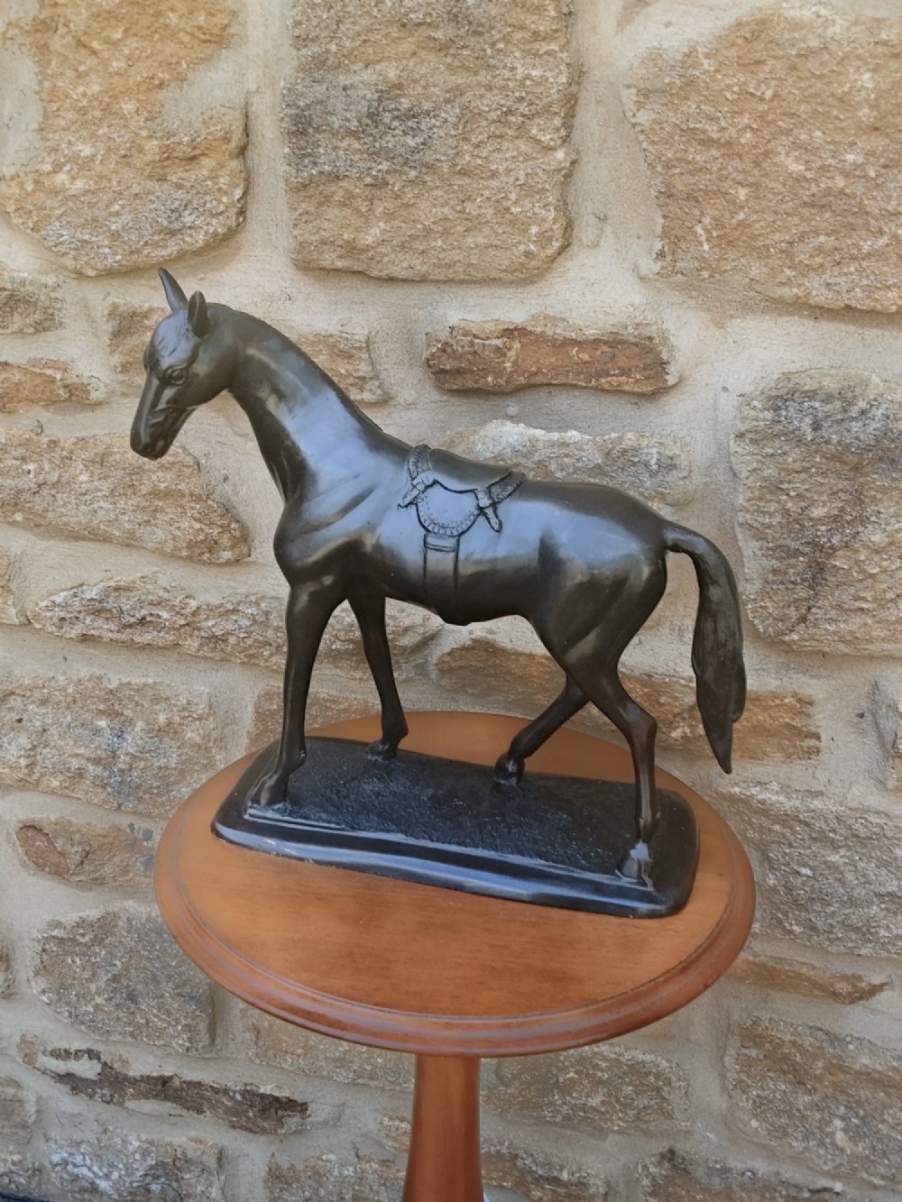 A dark brown cast bronze sculpture depicting a saddled standing horse positioned on an integral rectangular base. View XIII