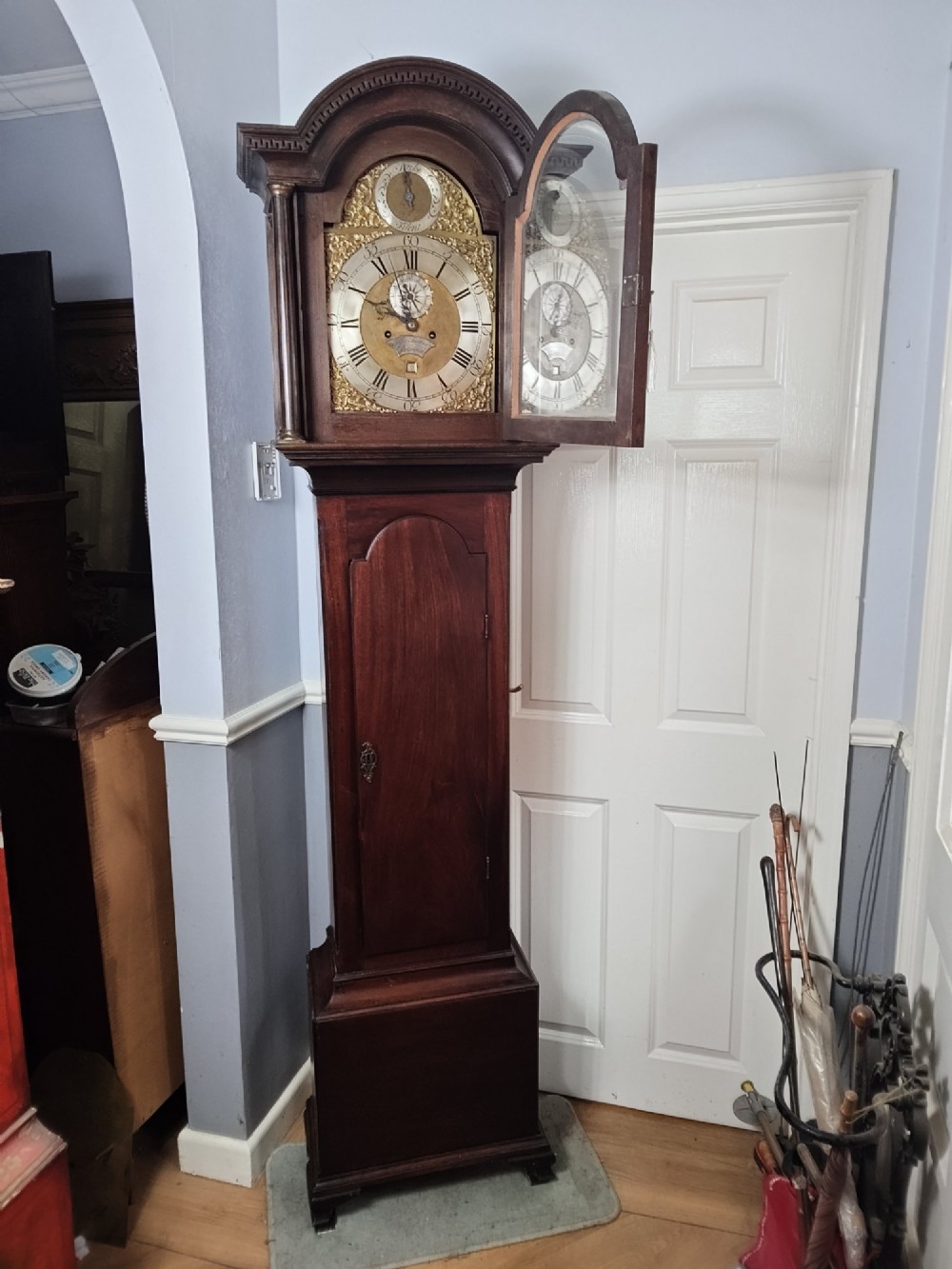 An antique Georgian longcase clock in dark mahogany featuring an arched hood and a brass dial with a strike-silent selector.