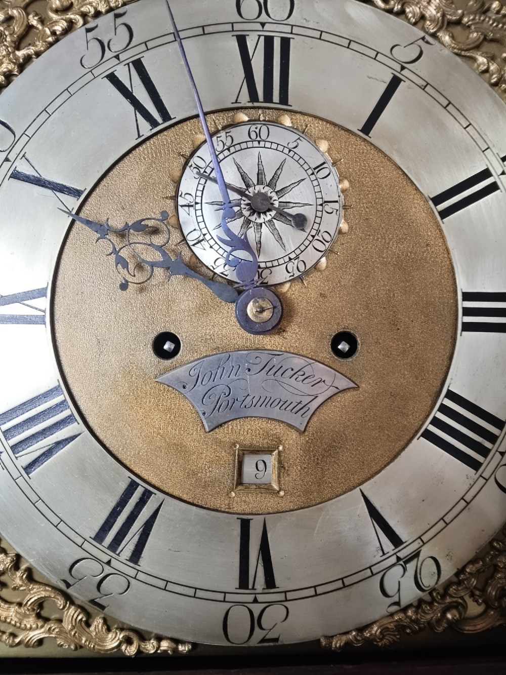 An antique Georgian longcase clock in dark mahogany featuring an arched hood and a brass dial with a strike-silent selector. View III