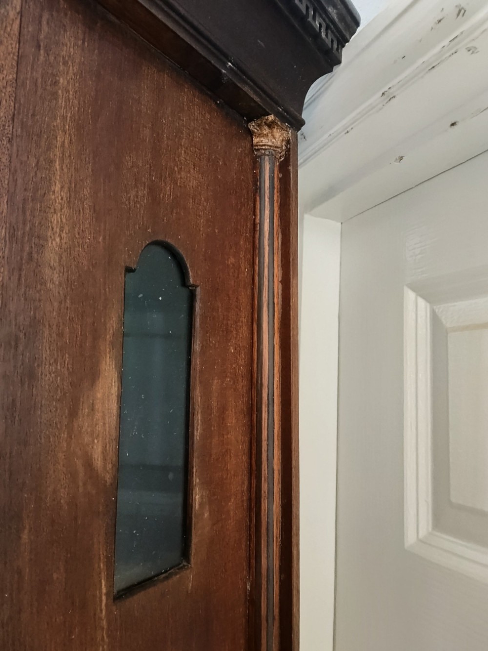 An antique Georgian longcase clock in dark mahogany featuring an arched hood and a brass dial with a strike-silent selector. View VI