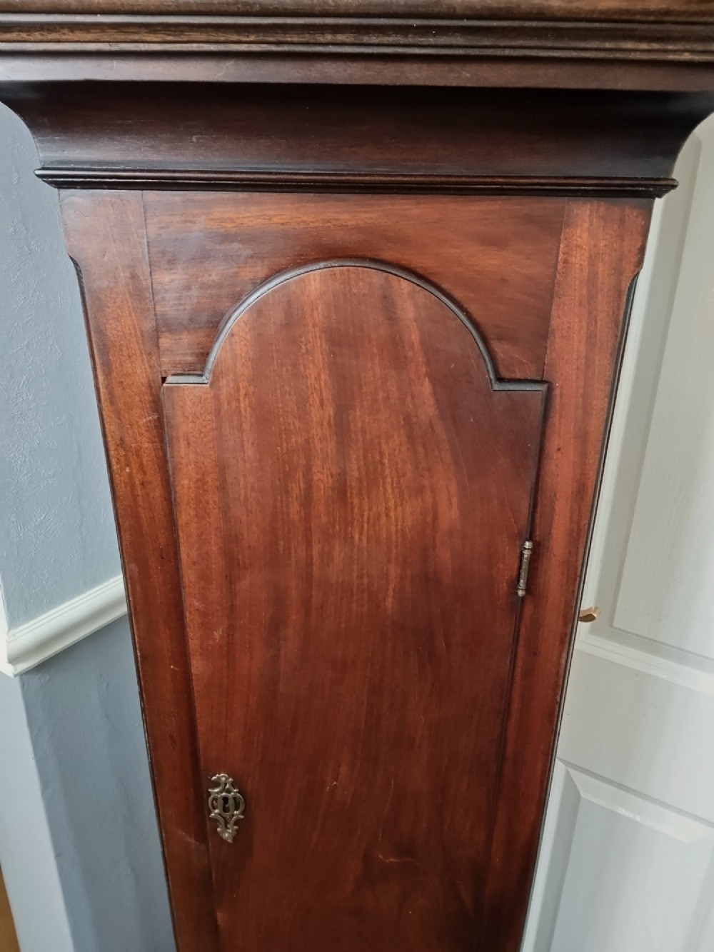 An antique Georgian longcase clock in dark mahogany featuring an arched hood and a brass dial with a strike-silent selector. View VIII