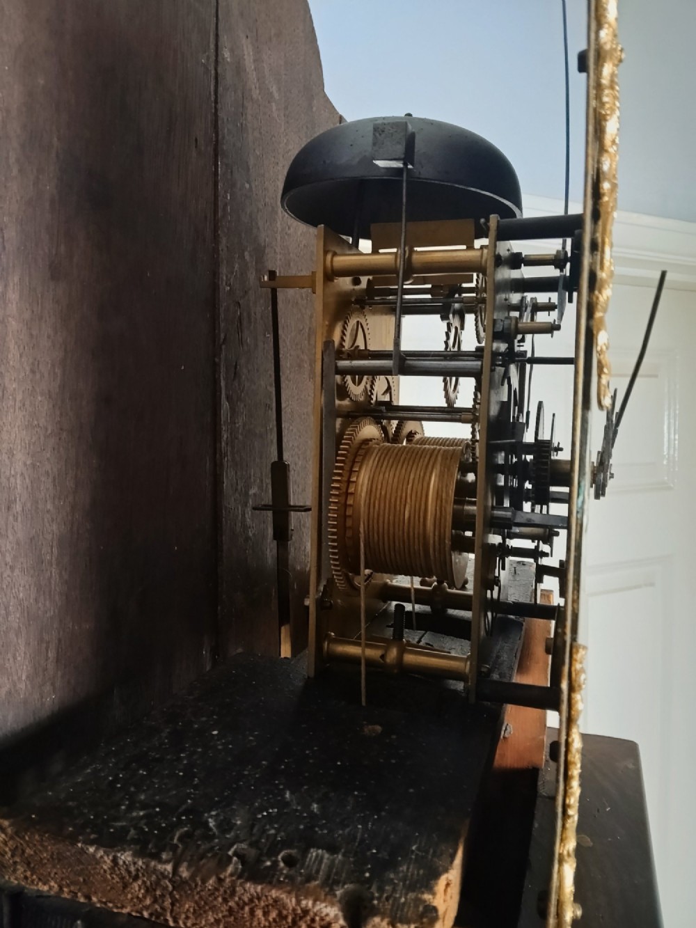 An antique Georgian longcase clock in dark mahogany featuring an arched hood and a brass dial with a strike-silent selector. View XI