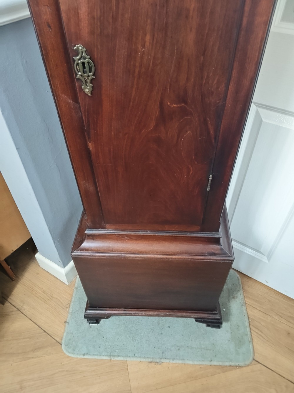 An antique Georgian longcase clock in dark mahogany featuring an arched hood and a brass dial with a strike-silent selector. View XIV