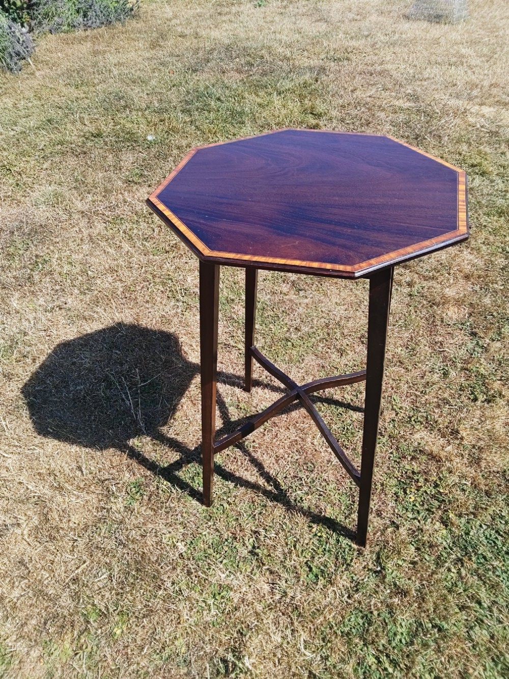 An octagonal dark mahogany side table featuring crossbanded timber inlay around the top surface and four tapered legs supported by an X-shaped stretcher. View II
