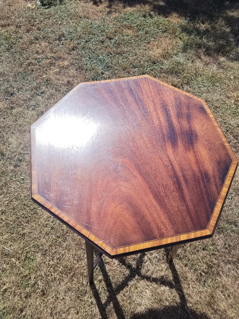 An octagonal dark mahogany side table featuring crossbanded timber inlay around the top surface and four tapered legs supported by an X-shaped stretcher. View III