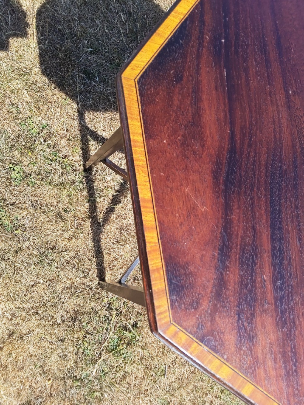 An octagonal dark mahogany side table featuring crossbanded timber inlay around the top surface and four tapered legs supported by an X-shaped stretcher. View V