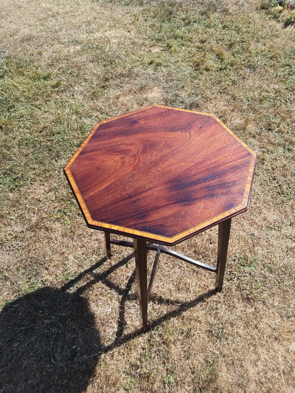 An octagonal dark mahogany side table featuring crossbanded timber inlay around the top surface and four tapered legs supported by an X-shaped stretcher. View VII