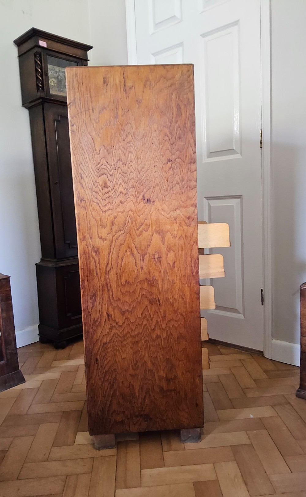 A tall oak tambour filing cabinet featuring a slatted wooden roll-front shutter door with a key inserted near the upper handle. View VII