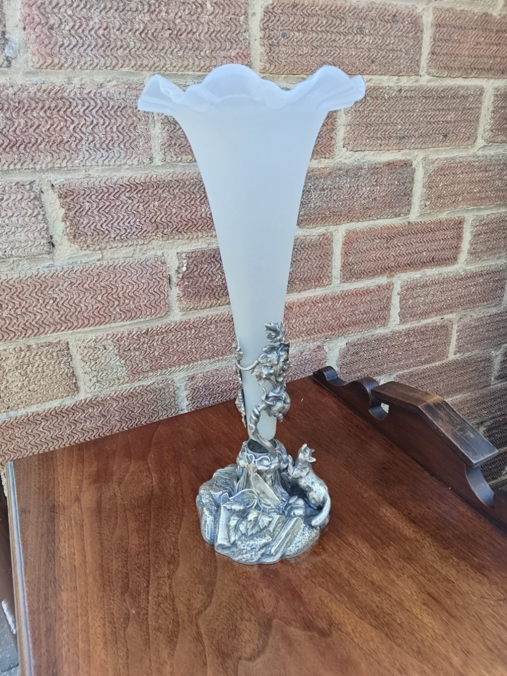A Victorian white metal epergne base depicting a fox and grapes motif holding a frosted opaque glass trumpet vase with a ruffled rim. View II
