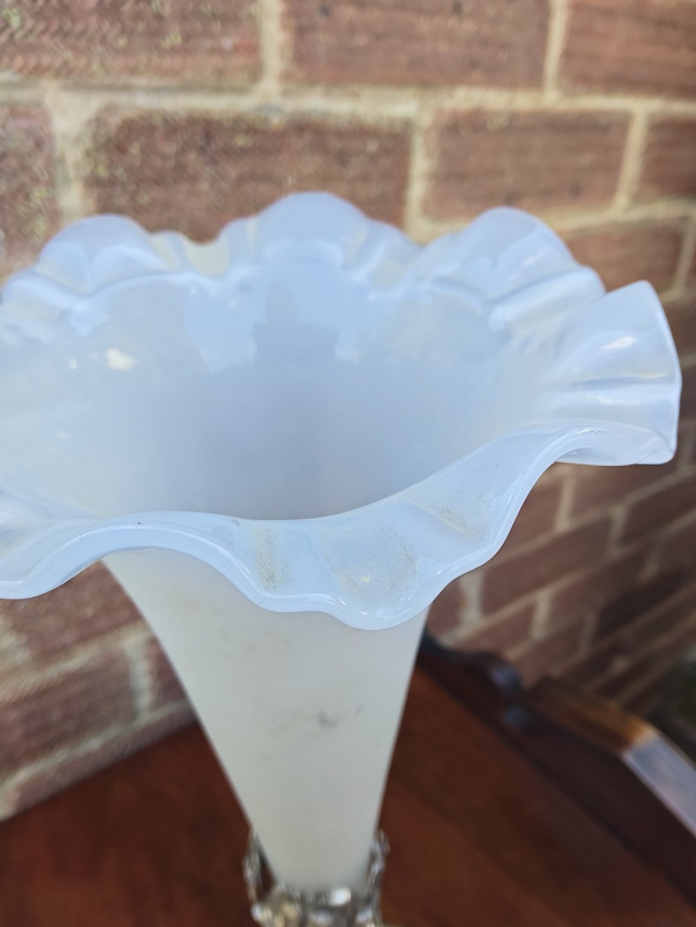 A Victorian white metal epergne base depicting a fox and grapes motif holding a frosted opaque glass trumpet vase with a ruffled rim. View V