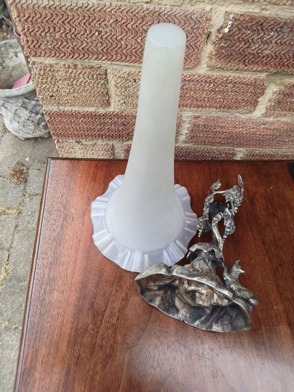 A Victorian white metal epergne base depicting a fox and grapes motif holding a frosted opaque glass trumpet vase with a ruffled rim. View X