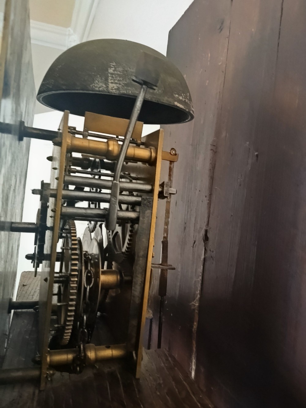 A freestanding Georgian oak longcase clock featuring a square brass dial, slender trunk door, turned hood columns, and a square plinth base. View VII