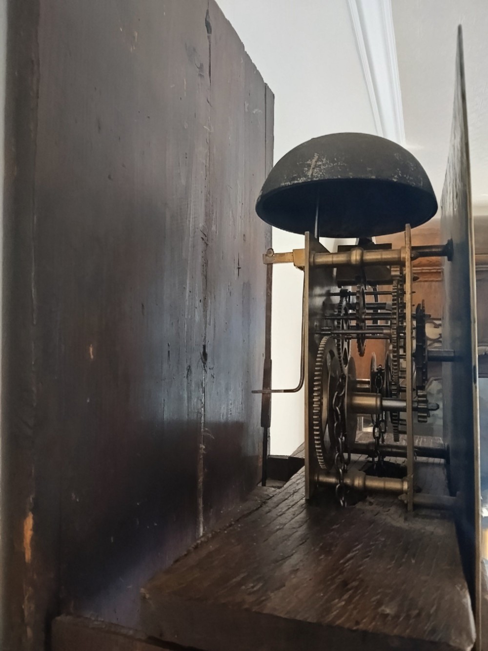 A freestanding Georgian oak longcase clock featuring a square brass dial, slender trunk door, turned hood columns, and a square plinth base. View VIII