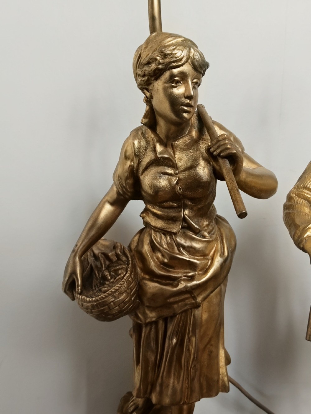 A pair of gold gilt metal table lamps depicting standing figures of French rustic workers mounted on square wooden bases. View II