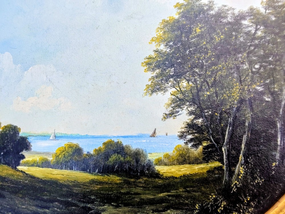 An oval oil painting depicting a grassy coastal landscape with trees, a distant church tower, and sailboats on the blue sea beneath a cloudy sky, encased in a gilt frame. View VIII