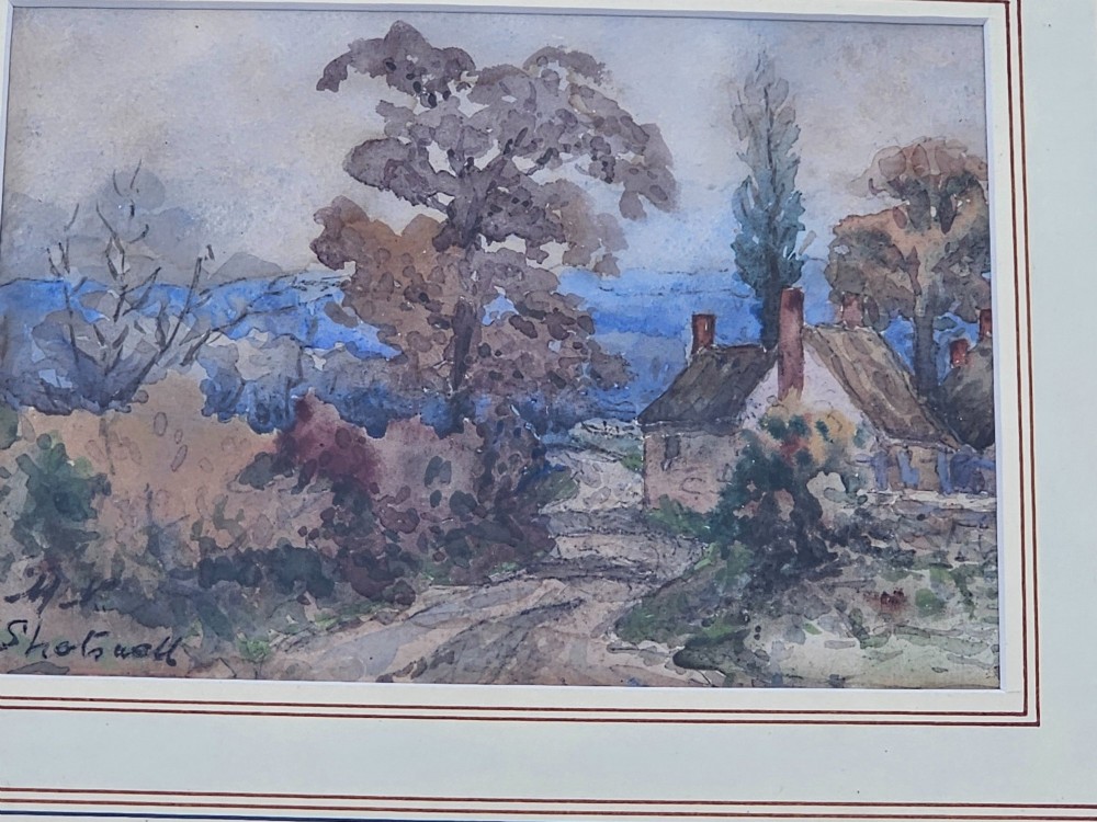 An early 20th-century framed watercolour painting depicting a country cottage with a thatched roof, brickwork, and flowering garden. View IV
