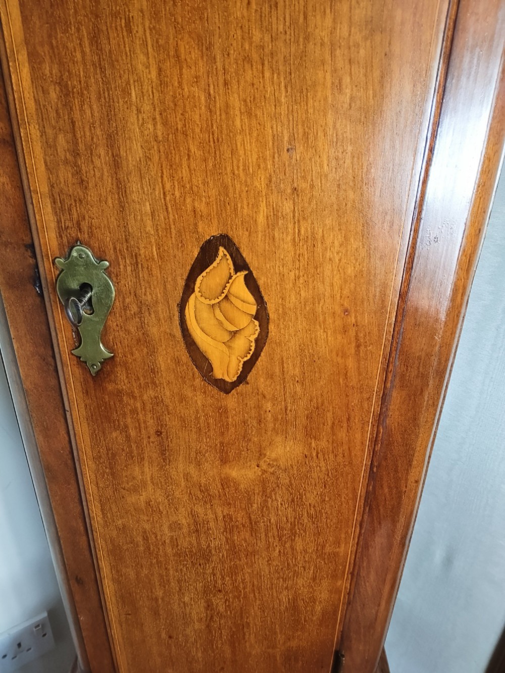 A 19th-century mahogany grandfather clock featuring a swan-neck pediment, brass arch dial, and decorative inlaid paterae on the trunk door. View III