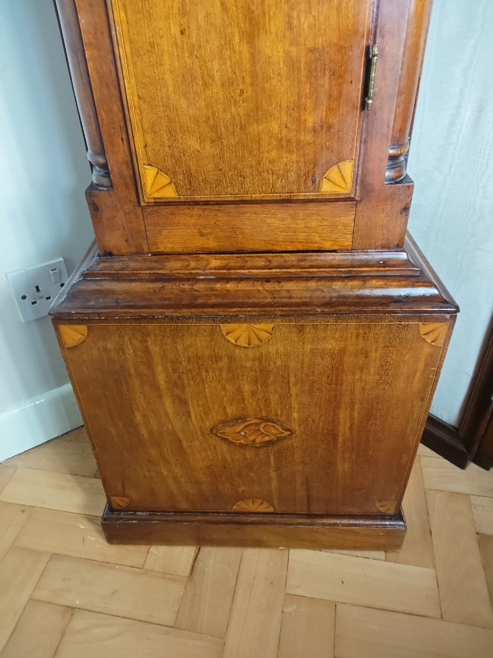 A 19th-century mahogany grandfather clock featuring a swan-neck pediment, brass arch dial, and decorative inlaid paterae on the trunk door. View IV