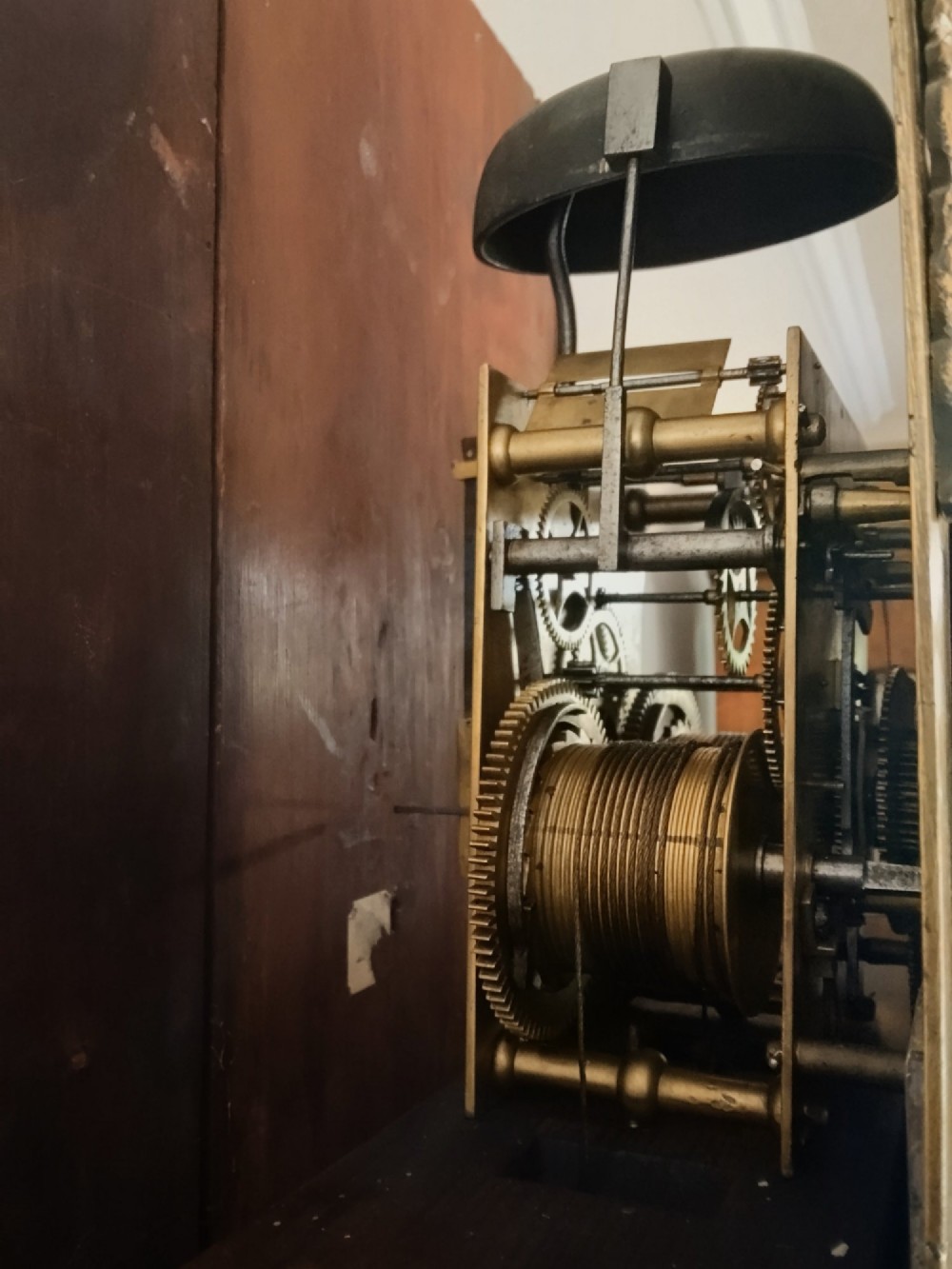 A 19th-century mahogany grandfather clock featuring a swan-neck pediment, brass arch dial, and decorative inlaid paterae on the trunk door. View VII