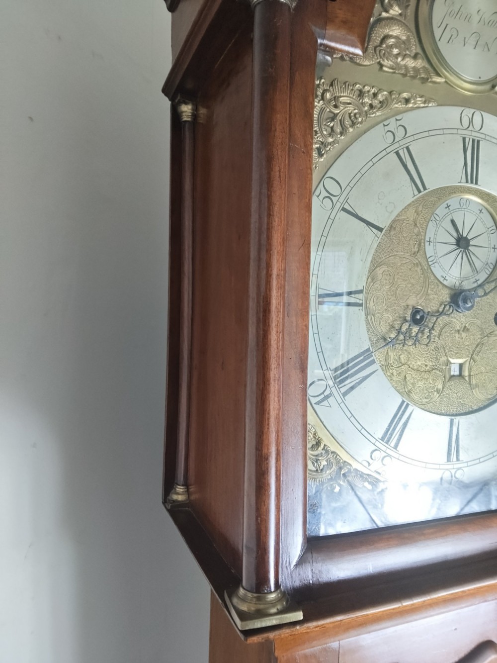 A 19th-century mahogany grandfather clock featuring a swan-neck pediment, brass arch dial, and decorative inlaid paterae on the trunk door. View IX