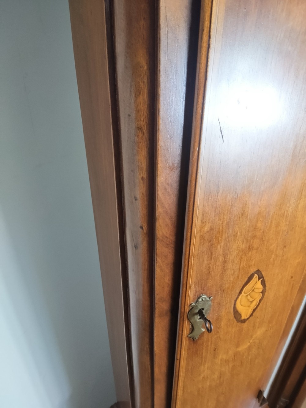 A 19th-century mahogany grandfather clock featuring a swan-neck pediment, brass arch dial, and decorative inlaid paterae on the trunk door. View X