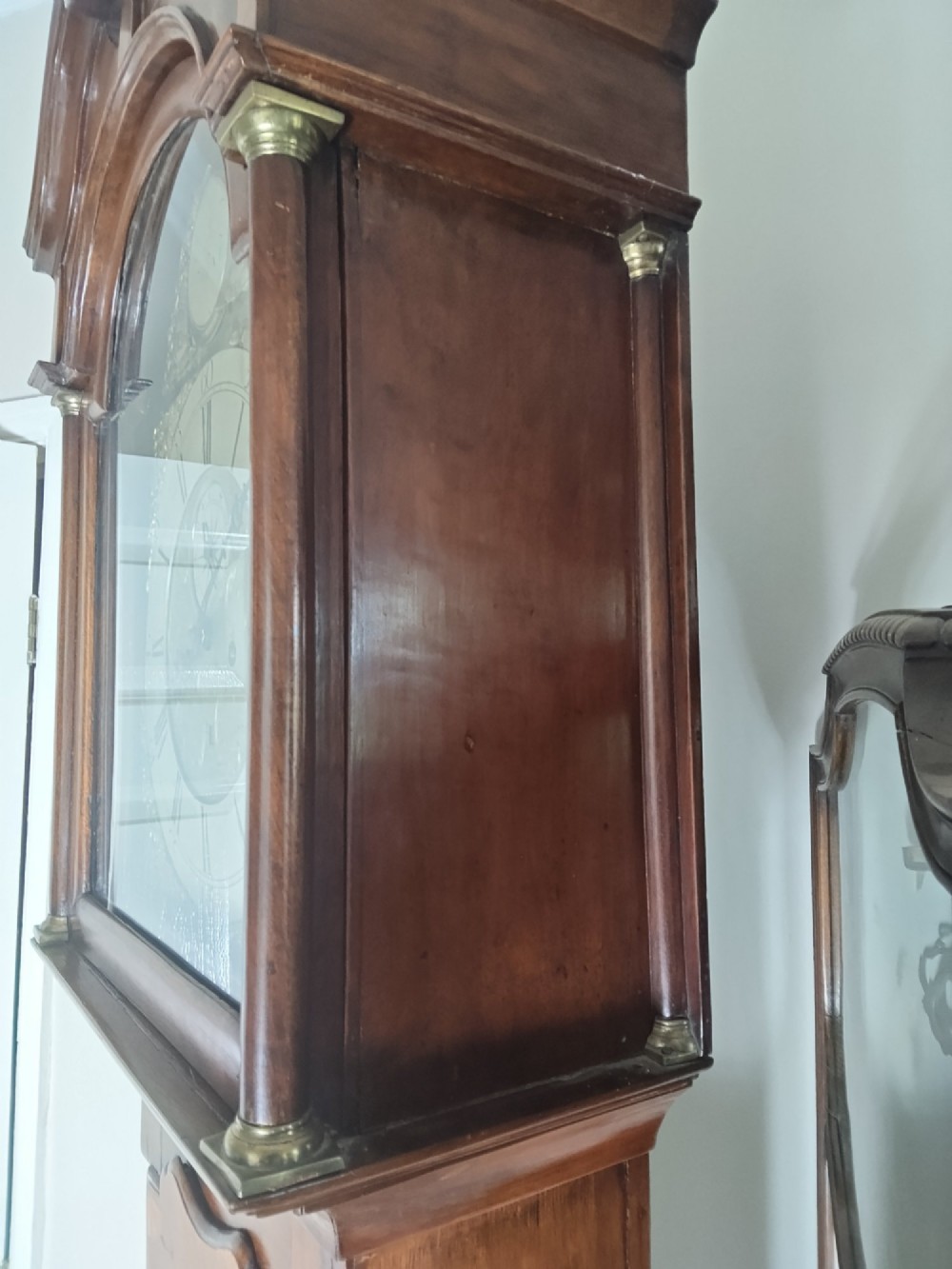 A 19th-century mahogany grandfather clock featuring a swan-neck pediment, brass arch dial, and decorative inlaid paterae on the trunk door. View XII