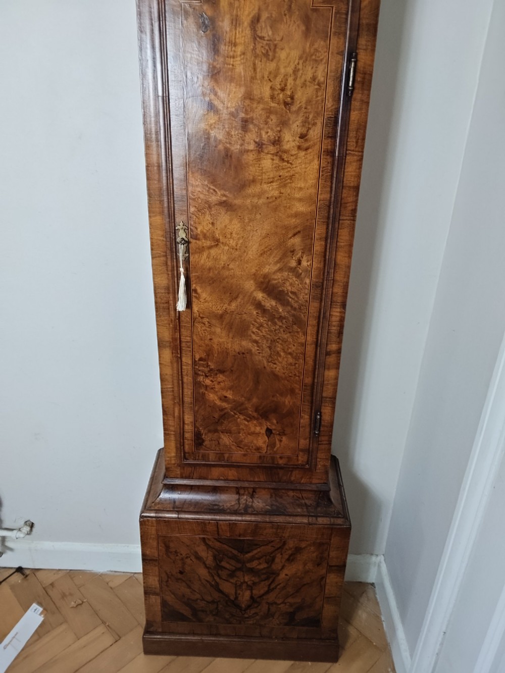 An early Georgian longcase clock featuring a burr walnut veneered case, an arched hood, and a brass dial with Roman numerals. View II