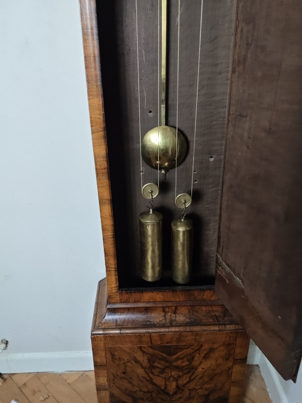 An early Georgian longcase clock featuring a burr walnut veneered case, an arched hood, and a brass dial with Roman numerals. View X