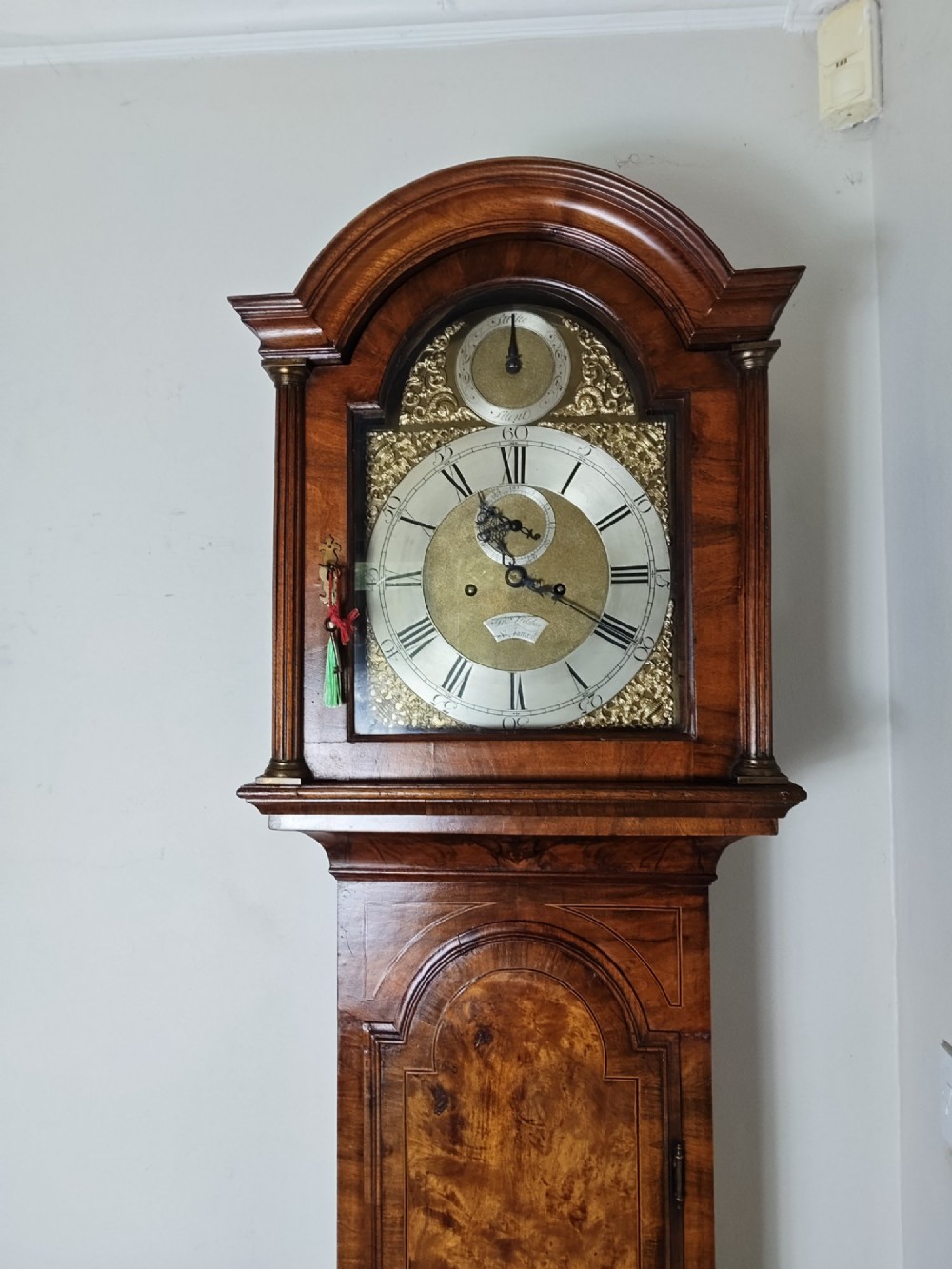 An early Georgian longcase clock featuring a burr walnut veneered case, an arched hood, and a brass dial with Roman numerals. View XI