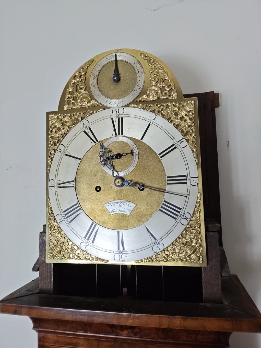 An early Georgian longcase clock featuring a burr walnut veneered case, an arched hood, and a brass dial with Roman numerals. View XII