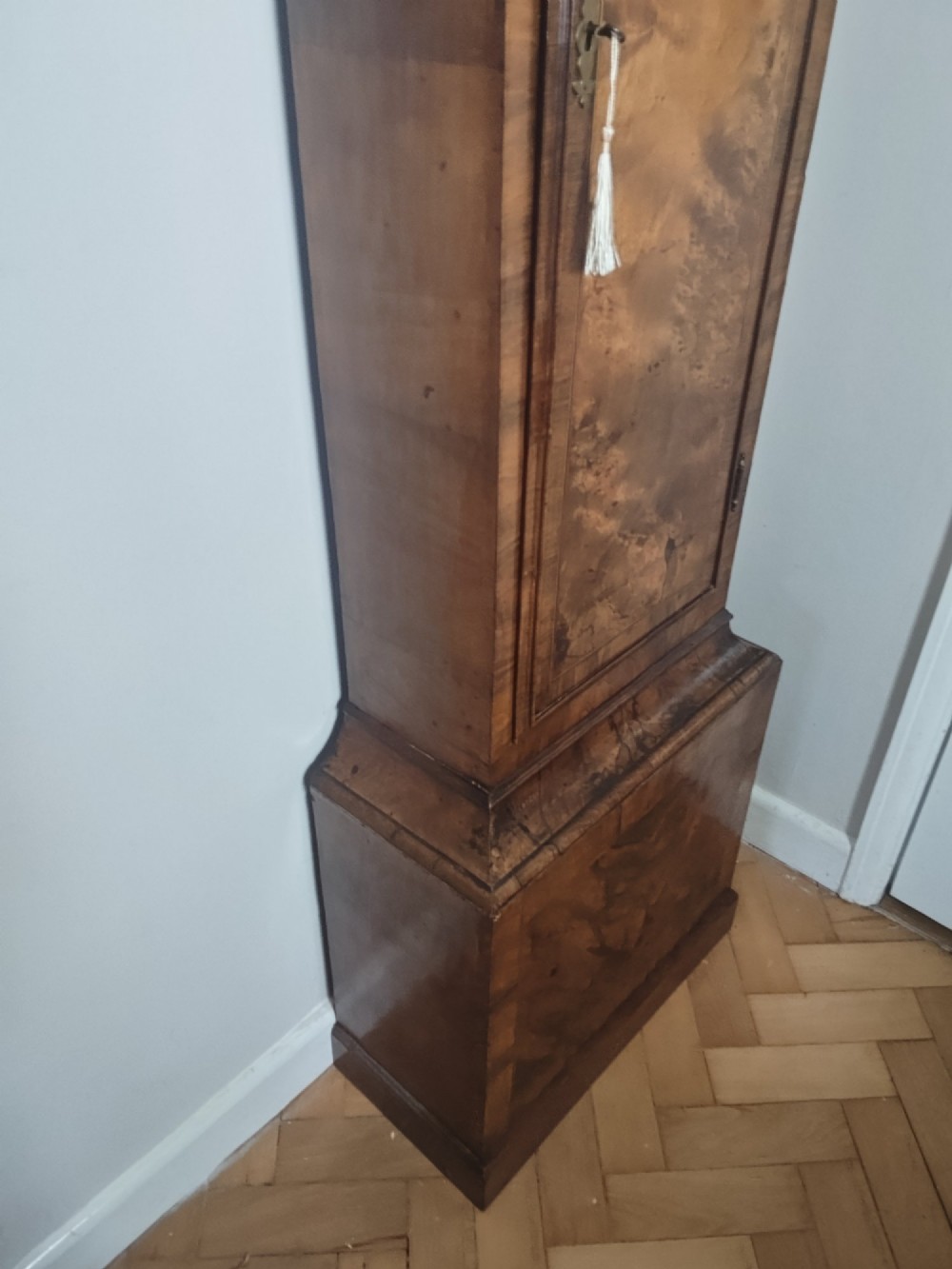 An early Georgian longcase clock featuring a burr walnut veneered case, an arched hood, and a brass dial with Roman numerals. View XIV