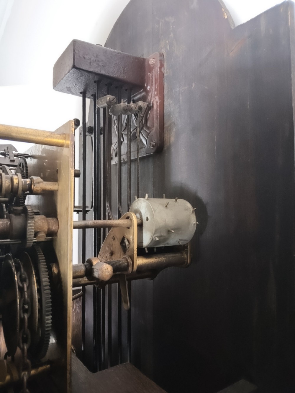 A 1920s dark oak grandmother longcase clock featuring an arched top hood, barley twist columns, brass dial, and glazed door displaying weights. View VI