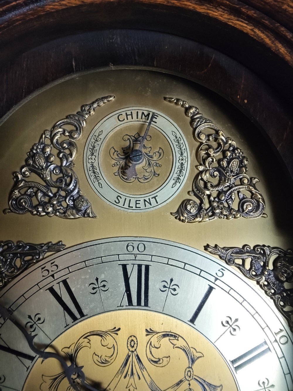 A 1920s dark oak grandmother longcase clock featuring an arched top hood, barley twist columns, brass dial, and glazed door displaying weights. View VIII