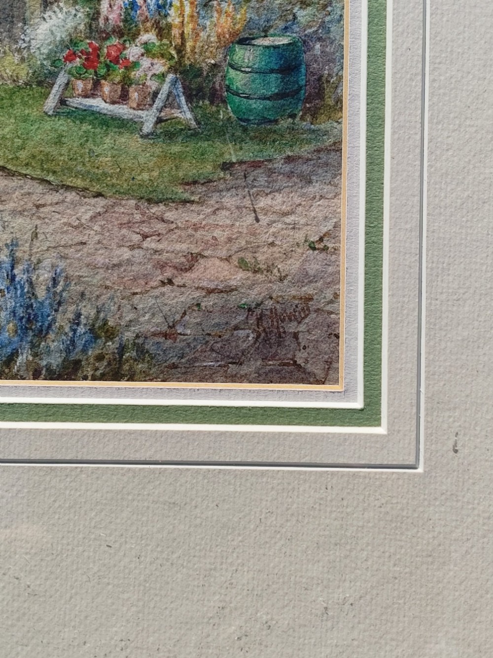 A framed vertical watercolour painting depicting a traditional thatched cottage with a garden filled with colourful flowers under a blue sky. View IV