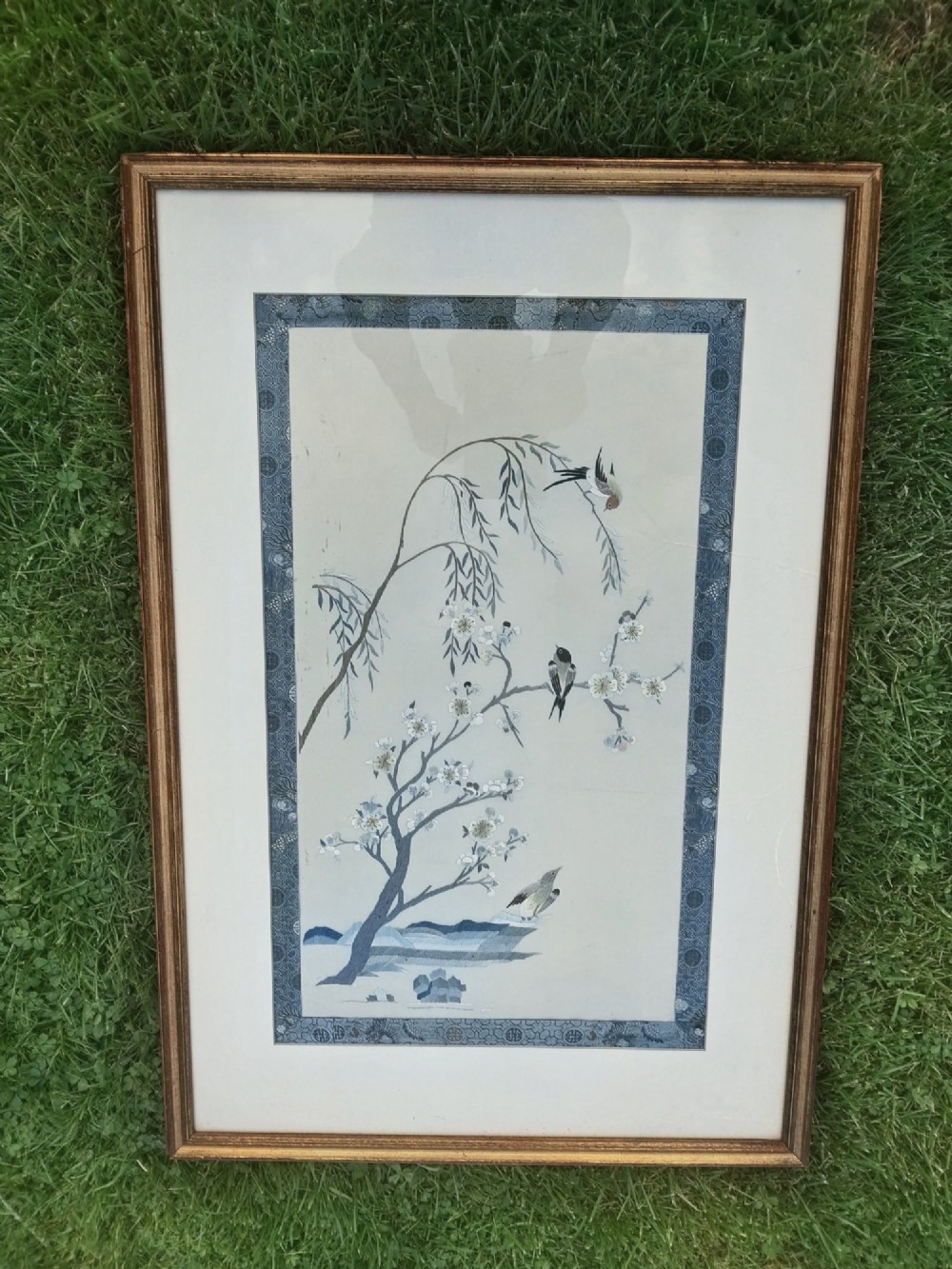 A framed Chinese silk embroidery picture depicting birds perched among blossoming branches and willow leaves on a neutral cream background with a decorative blue brocade border. View VI