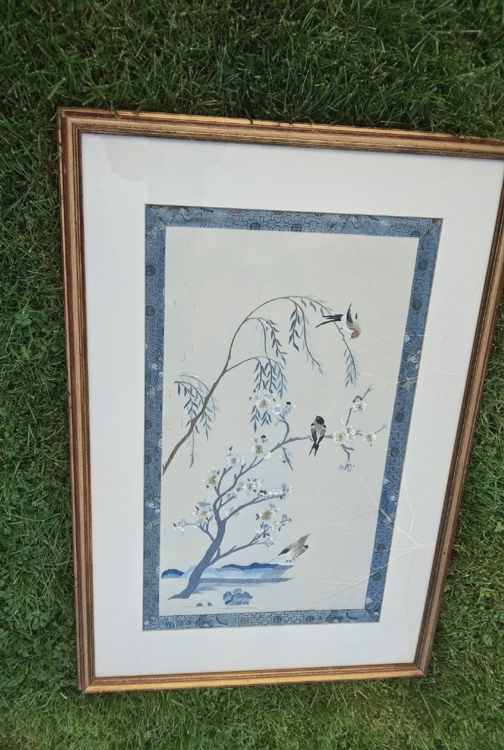 A framed Chinese silk embroidery picture depicting birds perched among blossoming branches and willow leaves on a neutral cream background with a decorative blue brocade border. View VII