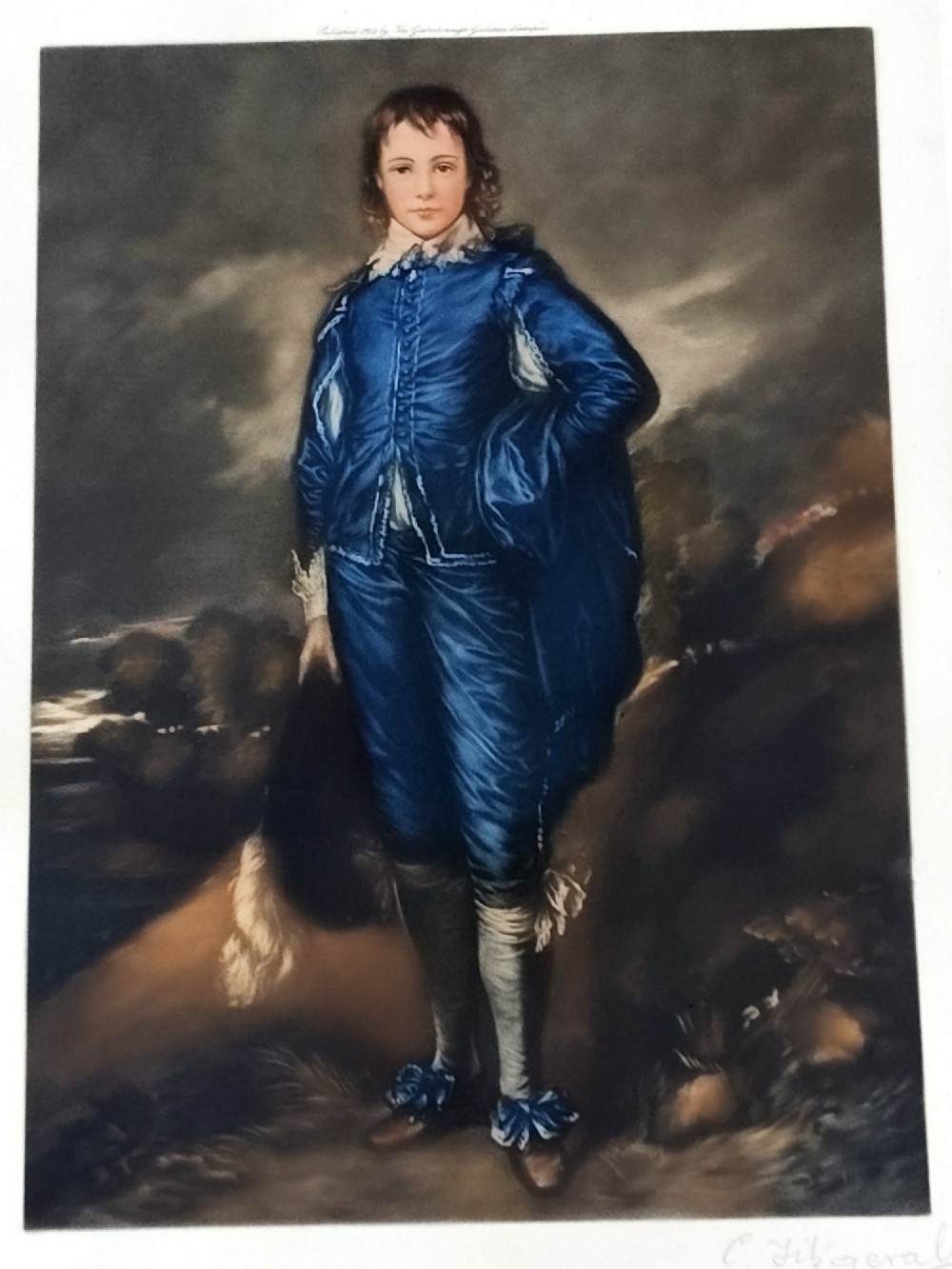A framed colour portrait print of Thomas Gainsboroughs The Blue Boy, set within a wide beige mount and a gold giltwood frame topped with a bow cresting. View III