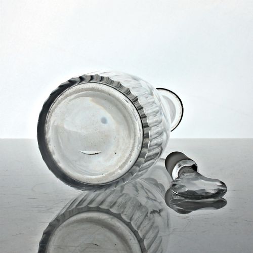 fig 2. A clear Georgian cut glass spirit decanter featuring vertical fluted cuts along the base, facet cutting on the upper neck, and a faceted round stopper.