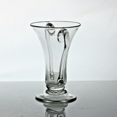 fig 1. A clear Georgian hand-blown glass cup featuring two curved side handles, a flared rim, and a thick pedestal base.