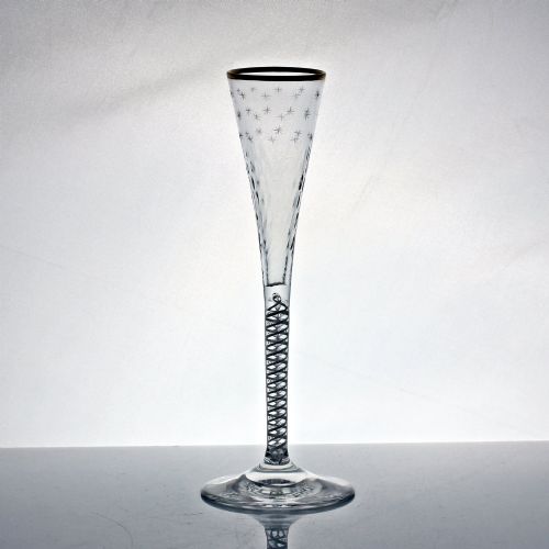 fig 1. A tall Georgian clear lead glass ratafia flute featuring an engraved star pattern, gilded rim, white double series opaque twist stem, and a flat circular foot.