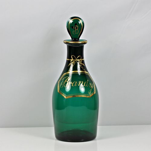 fig 1. A set of three Georgian Bristol green glass decanters with gilded labels for Brandy, Hollands, and Rum, featuring monograms on the disc stoppers.