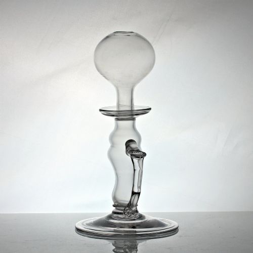 fig 1. A tall clear hand-blown glass Georgian oil lamp featuring a bulbous top reservoir, a drip tray, a baluster stem, and an applied side handle on a broad circular foot.