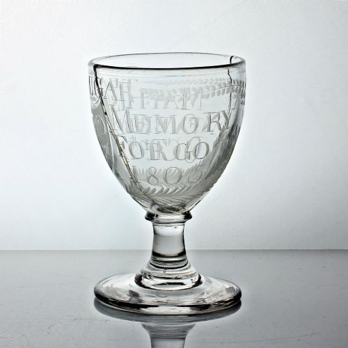fig 1. An antique clear glass rummer featuring hand-engraved naval motifs, text referencing Trafalgar, a short stem, and a circular foot.