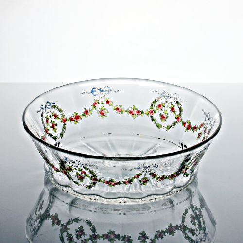 fig 1. An oval clear glass bowl featuring hand-painted enamelled garlands of red roses, green foliage, and blue ribbons along the exterior with a gilded rim.