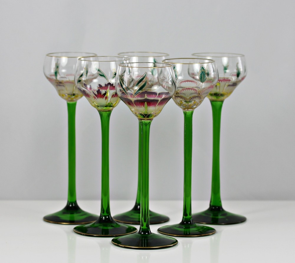 A set of six Art Nouveau style cordial glasses featuring tall, slender green stems and clear bowls decorated with hand-painted enamel floral motifs in pink, green, and white. View II